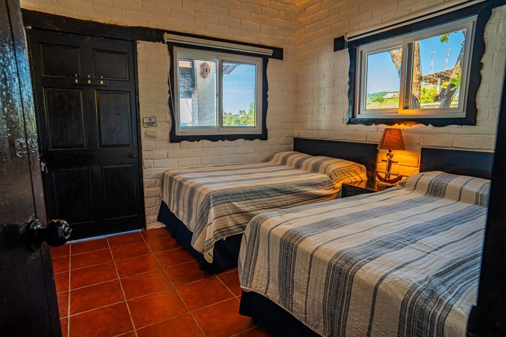 Une chambre avec deux lits, une fenêtre donnant sur un paysage agréable et une porte.