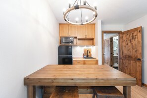 Una cucina moderna con mobili in legno, un frigorifero nero, un forno a microonde e un tavolo da pranzo in legno con panche.