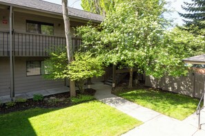 A two-story building with a covered porch, a small tree, and a well-maintained lawn. - New! Cozy Condo at Marina Cay | Flathead Lake, Glacier & Bigfork Village (Bigfork)
