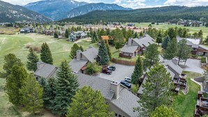 A residential area with houses, a parking lot, and a mountainous backdrop. - Nordic Pines Retreat | Ski, Golf & Unwind (Big Sky)