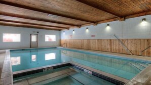 An indoor swimming pool with wooden beams on the ceiling, tiled walls, and a clear water surface. - Nordic Pines Retreat | Ski, Golf & Unwind (Big Sky)