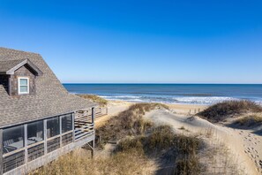 Ein Objekt direkt am Strand mit einer Holzterrasse, einem Wintergarten und Blick aufs Meer.