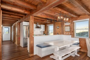 Interior em madeira com cozinha, sala de jantar e um banco.