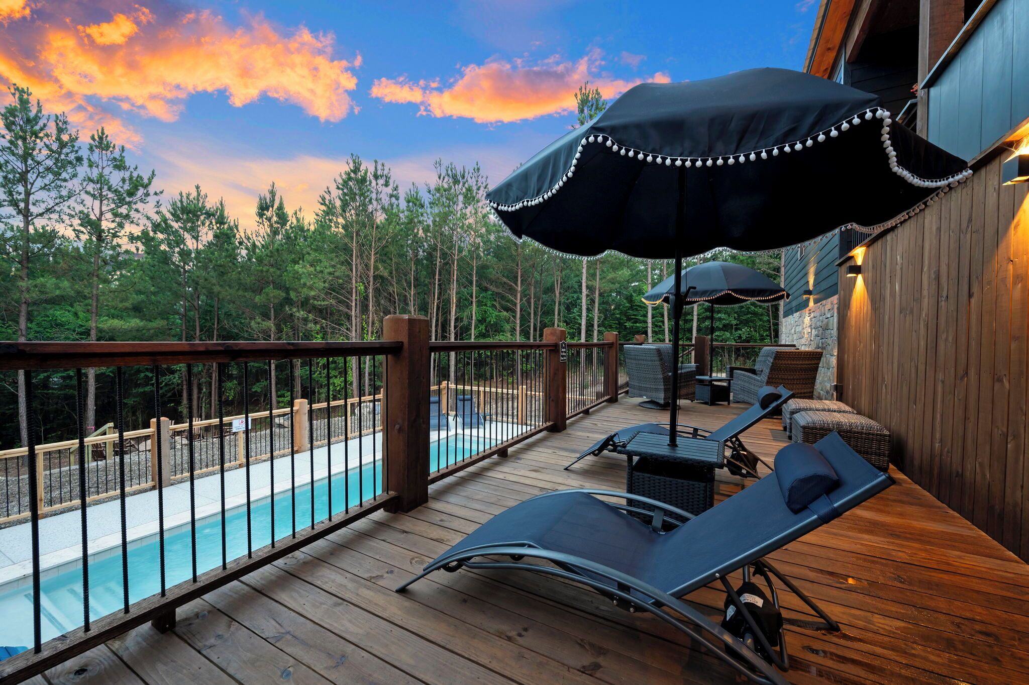 Une terrasse en bois avec une piscine, des chaises longues et des parasols.
