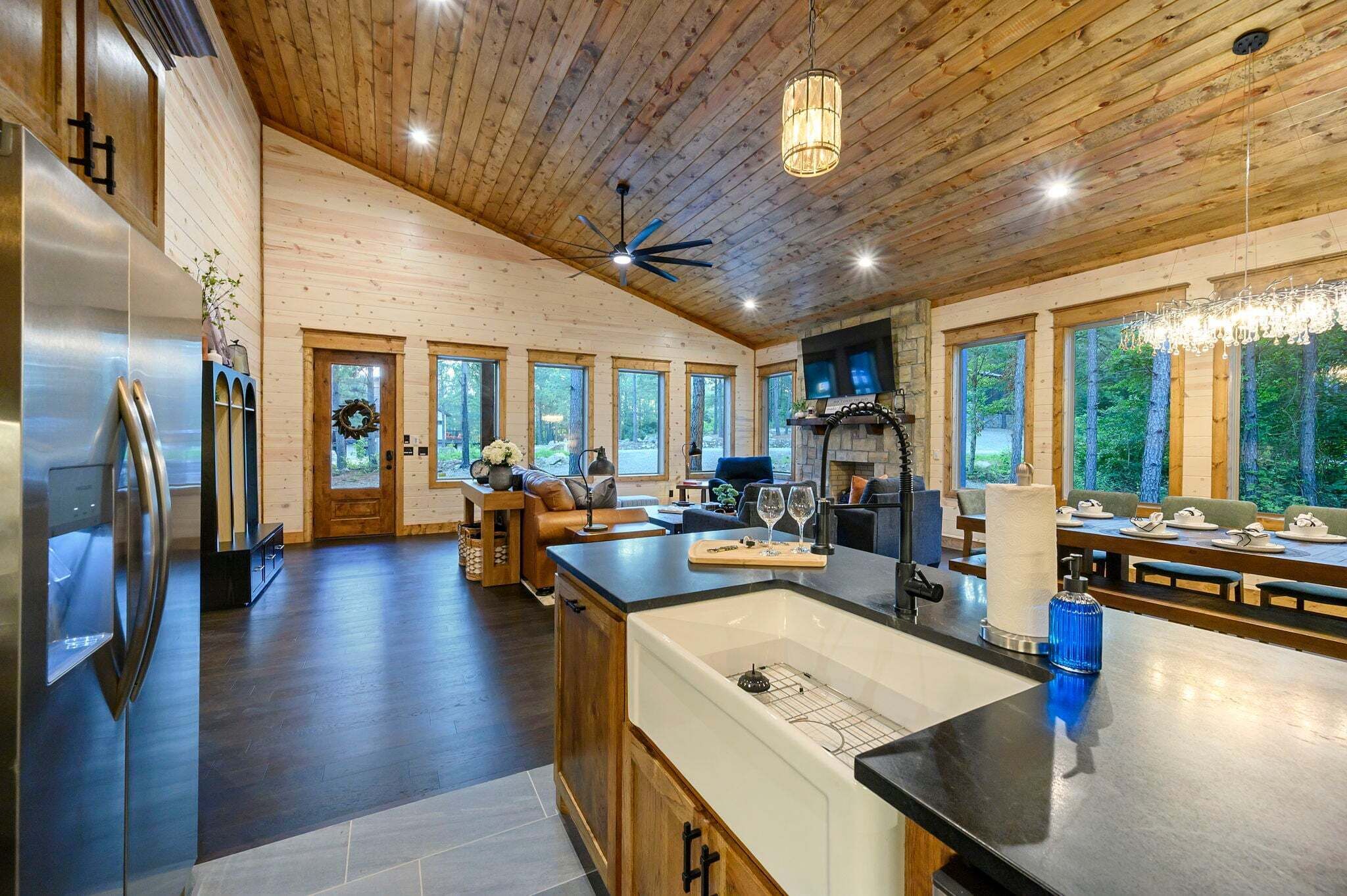 Une cuisine spacieuse dotée d’un grand îlot central, d’un plafond en bois et de grandes fenêtres.