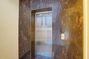 An elevator with a metallic interior and a digital display on the wall.
