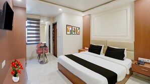 Une chambre d’hôtel avec un grand lit, des tables de chevet, une télévision et un petit coin salon comprenant une table et une chaise.