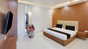 Une chambre d’hôtel moderne dotée d’un grand lit, de tables de chevet, d’une télévision et d’un petit coin salon avec une table et des chaises.