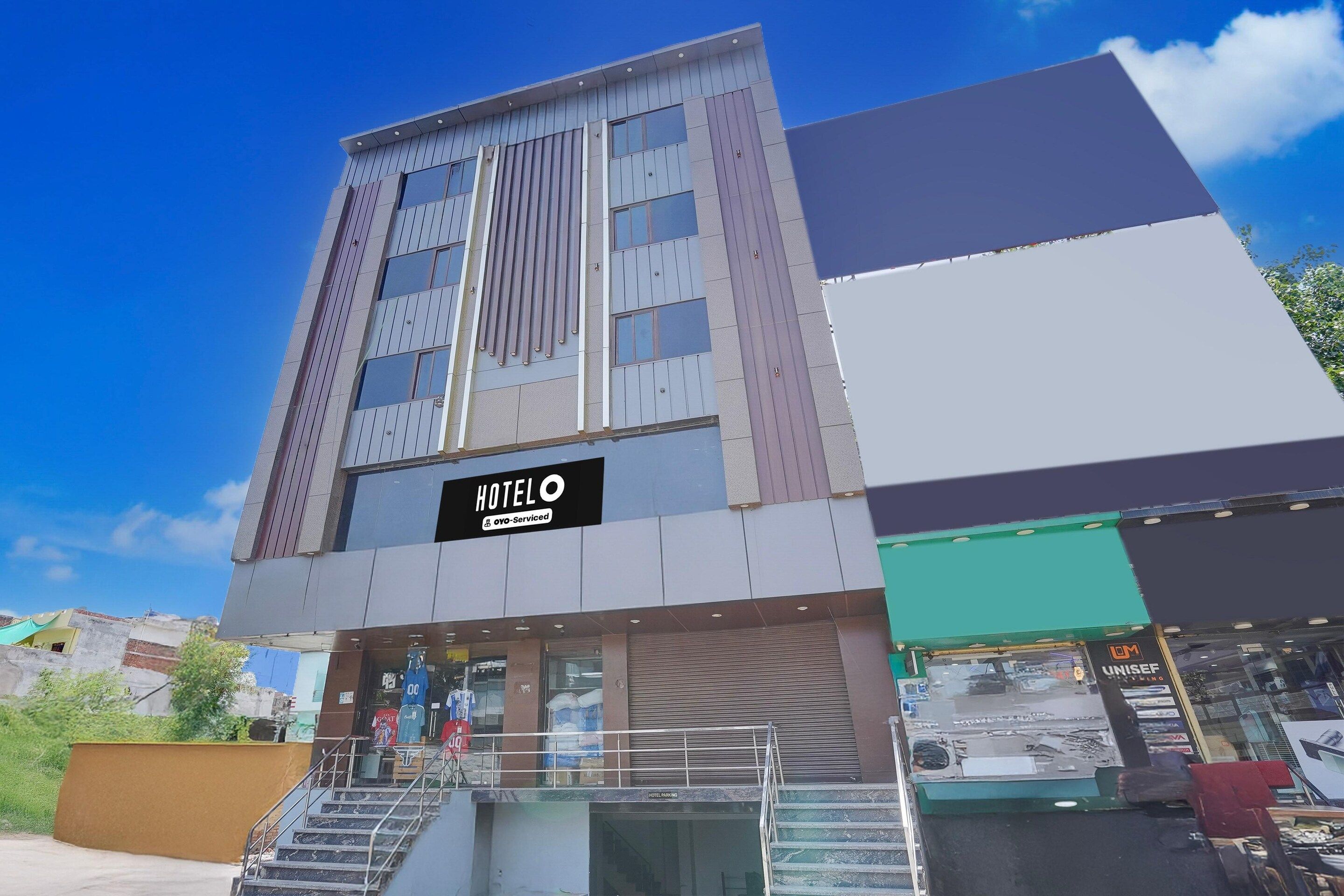 A hotel with a modern facade, a visible entrance, and a staircase leading to the entrance.