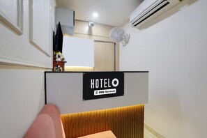 A hotel room with a bed, a minibar, a mirror, an air conditioner, and a sign indicating the room is serviced by OYO.