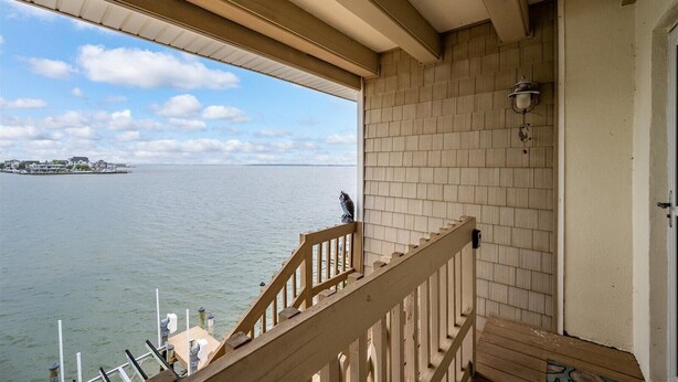 Een houten balkon met uitzicht op het water en een eiland in de verte.