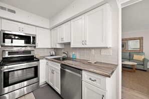 Eine moderne Küche mit weißen Schränken, Edelstahlgeräten und einer Holzausziehtafel.