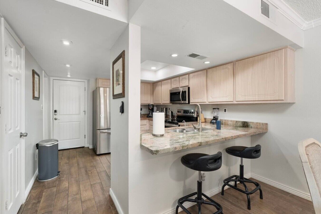 A kitchen with a marble countertop, stainless steel appliances, and wooden cabinets.