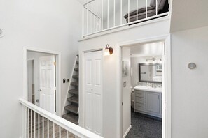 Una escalera conduce a un balcón en el segundo piso, con vistas al exterior.