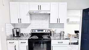 A kitchen with white cabinets, a stainless steel stove, and a coffee maker. - Modern Luxe Retreat - Fully Furnished Short-Term Rental in Lakeland (Lakeland)