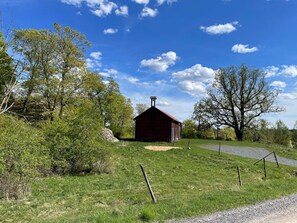 A red barn with a chimney, surrounded by green grass and trees. - 3 Person Holiday Home in Malmkoping (Malmkoping)
