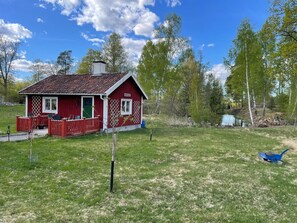 A red wooden house with a fenced porch and a small garden. - 3 Person Holiday Home in Malmkoping (Malmkoping)