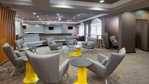 A modern lounge area with sofas, armchairs, and round tables. - SpringHill Suites | Queen Suite | Outlets, Winery, Merchants Sq (Williamsburg)