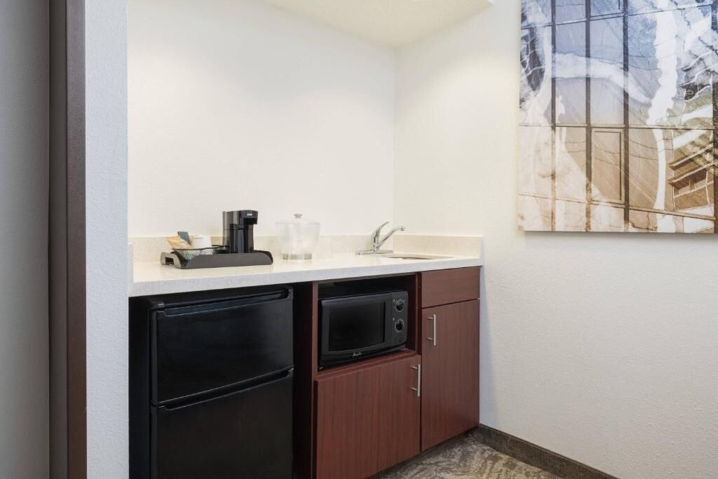 A compact kitchenette with a refrigerator, microwave, sink, and coffee maker.