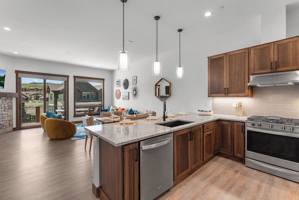 A modern kitchen with wooden cabinets, stainless steel appliances, and pendant lighting. - Downtown WP Villa 168 I Private Hot Tub I Great Views I Bunk Room I Discounted Attractions (Fraser)