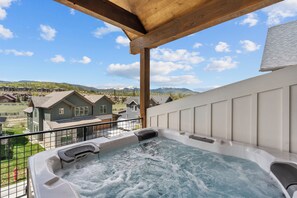 A hot tub with a wooden pergola overhead, a view of houses, and mountains in the background. - Downtown WP Villa 168 I Private Hot Tub I Great Views I Bunk Room I Discounted Attractions (Fraser)