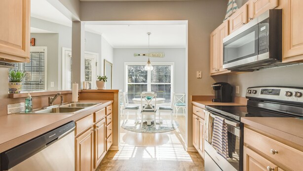 Una cocina moderna con armarios de madera, lavavajillas, estufa y microondas.
