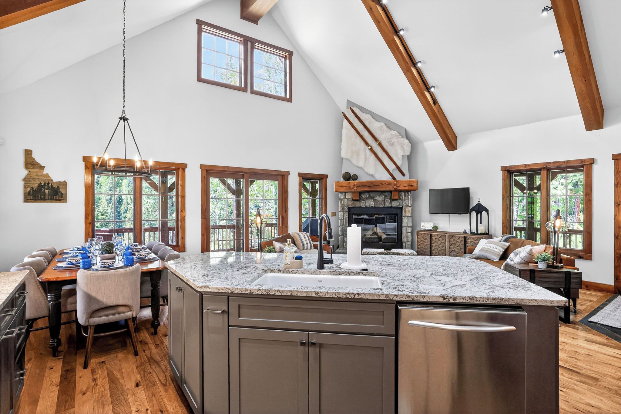 A spacious kitchen with a large island, wooden beams, and a stone fireplace.