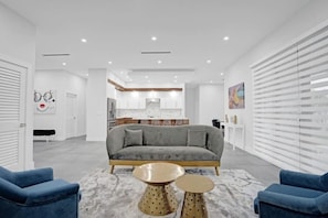 Ein modernes Wohnzimmer mit einem grauen Sofa, zwei runden Couchtischen und blauen Sesseln.