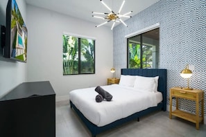 Ein Schlafzimmer mit Bett, Schreibtisch, Stuhl, Fenster und einer Wand mit Muster.