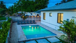 Una piscina con sillas de descanso, una valla de madera y una casa con el número 1930 en la fachada.