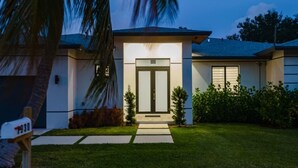 Una casa moderna de dos pisos con un césped cuidado, un buzón y un cielo despejado.