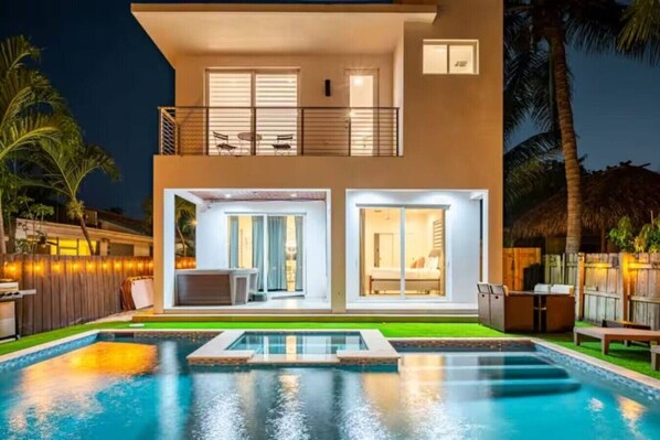 A two-story house with a swimming pool, a balcony, and a well-lit interior. - 2020 Built Modern Luxe Home Heated Pool & Jacuzzi (Hollywood)