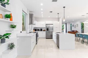 A modern kitchen with white cabinetry, stainless steel appliances, and a central island. - 2020 Built Modern Luxe Home Heated Pool & Jacuzzi (Hollywood)