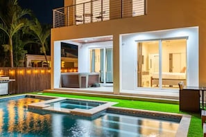 A modern house with a swimming pool, a barbecue area, and a well-lit interior. - 2020 Built Modern Luxe Home Heated Pool & Jacuzzi (Hollywood)