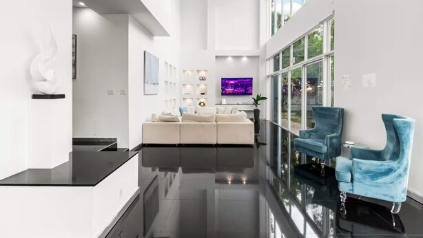 Een modern interieur met een witte bank, blauwe stoelen en een flatscreen televisie.