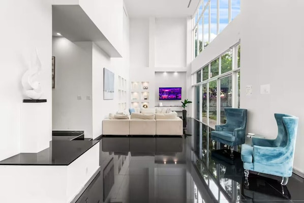 Ein modernes Interieur mit einem weißen Sofa, blauen Stühlen und einem Flachbildfernseher.