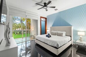 Ein modernes Hotelzimmer mit einem großen Bett, einem Deckenventilator, Blick ins Freie und einem Balkon.