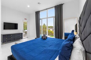 A modern hotel room with a large bed, a flat-screen TV, a dark-colored dresser, and a balcony with a view. - Modern Luxe 2021Built Heated Pool/Jacuzzi/Gameroom (Fort Lauderdale)