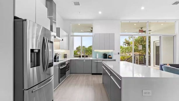 A modern kitchen with stainless steel appliances, grey cabinetry, and a large island. - Modern Luxe 2021Built Heated Pool/Jacuzzi/Gameroom (Fort Lauderdale)