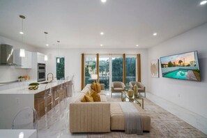 Ein modernes Wohnzimmer mit einer Couch, Sesseln, einem Couchtisch und einem Fernseher.