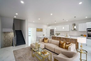 A modern living room with a sofa, coffee table, and a staircase. - Modern Beach Home 2022 Built (Pompano Beach)