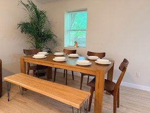 A dining table with chairs and a bench, surrounded by potted plants. - 4BR2BA Creekside Edgewood Retreat Near World Cup (Atlanta)