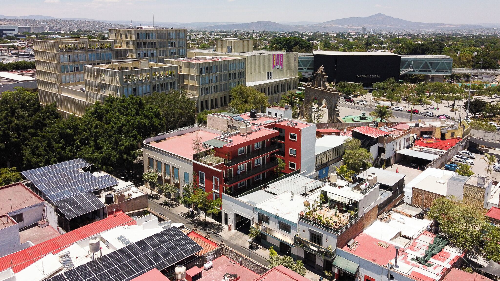 A cityscape with modern buildings, solar panels on rooftops, and a prominent Zapopan Centro building.