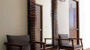 A hallway with two wooden chairs, a large mirror, and a patterned floor. - Gran Vila Nai Boutique Hotel (Zapopan)