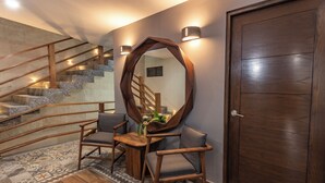 A staircase with wooden railings, a wooden table with chairs, a mirror, and a door. - Gran Vila Nai Boutique Hotel (Zapopan)