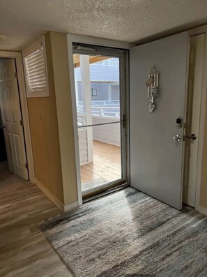 Ein Zimmer mit einer Schiebetür zum Balkon, einer Tür mit Schlüsselsperre und einem kleinen Teppich auf dem Boden.