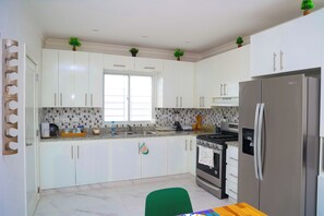 Eine moderne Küche mit weißen Schränken, einem Edelstahlkühlschrank und einem Fenster.
