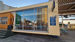 Ein modernes Gebäude mit großen Glasfenstern, einer Holzfassade und einem Schild, das es als Whirlpool- und Wellnessbereich kennzeichnet.