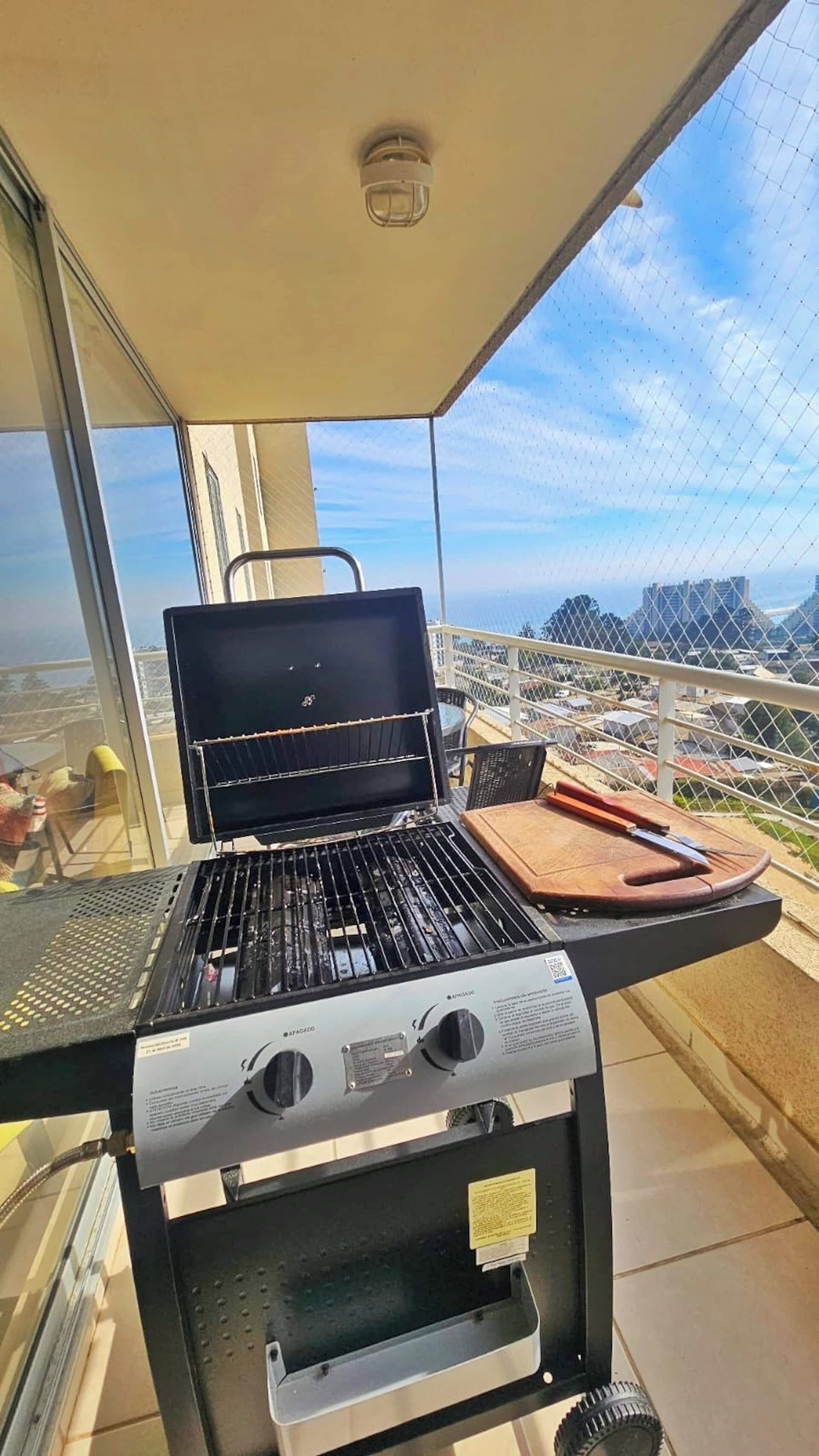 Un balcon équipé d’un barbecue, d’une planche à découper et d’un couteau.