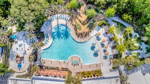 An aerial view of a resort with multiple swimming pools, sun loungers, and palm trees. - Mini Mouse House | Mini Golf & NO FEE Waterpark! (Davenport)